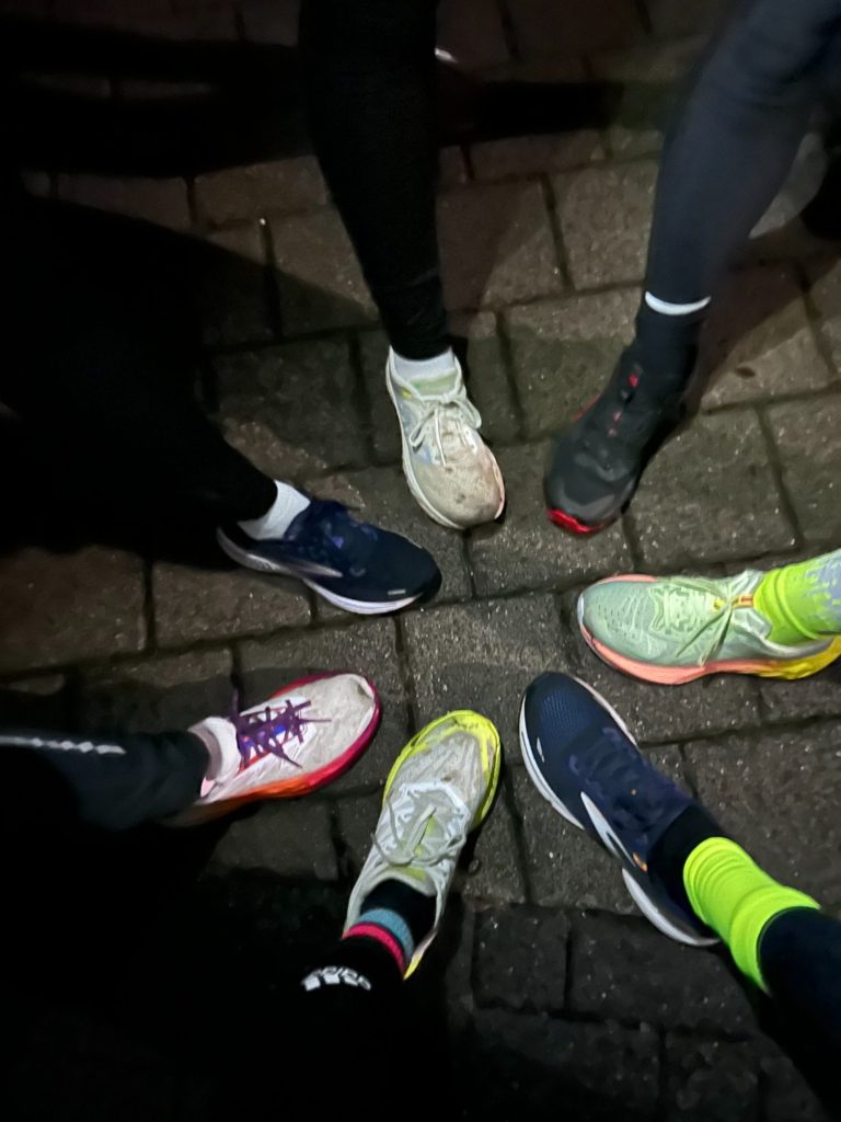 Hand hält Wanderstock auf einem Waldweg, Umgebungslicht durch Bäume gefiltert.